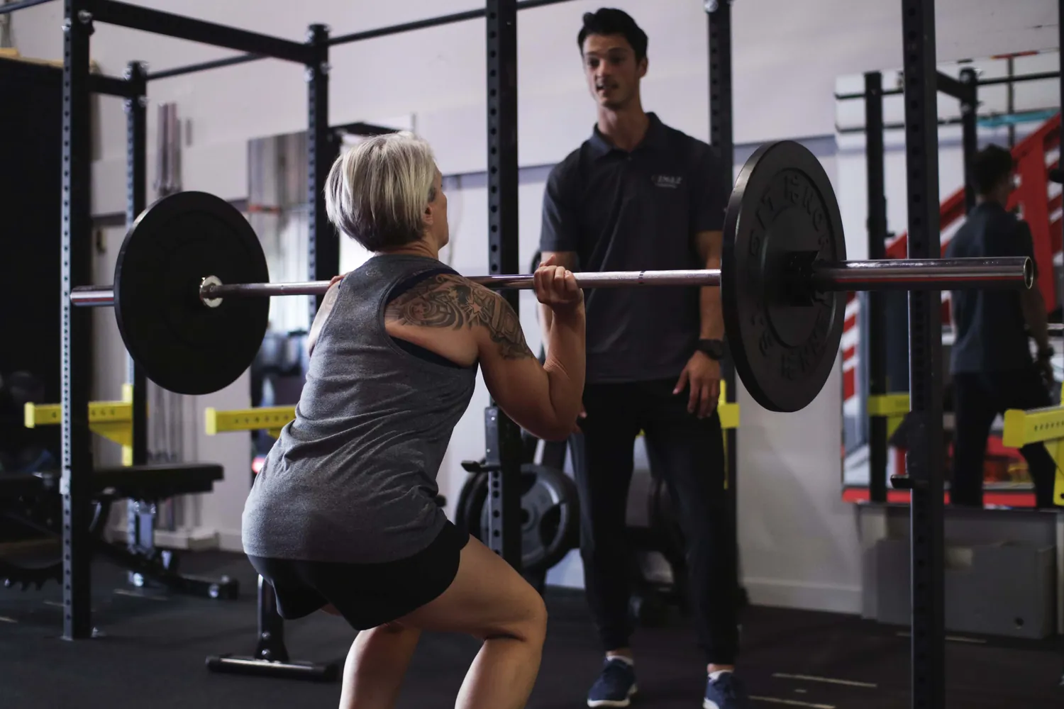 Senior client doing a clean lift with a trainer at Kenaz Training in Langley BC